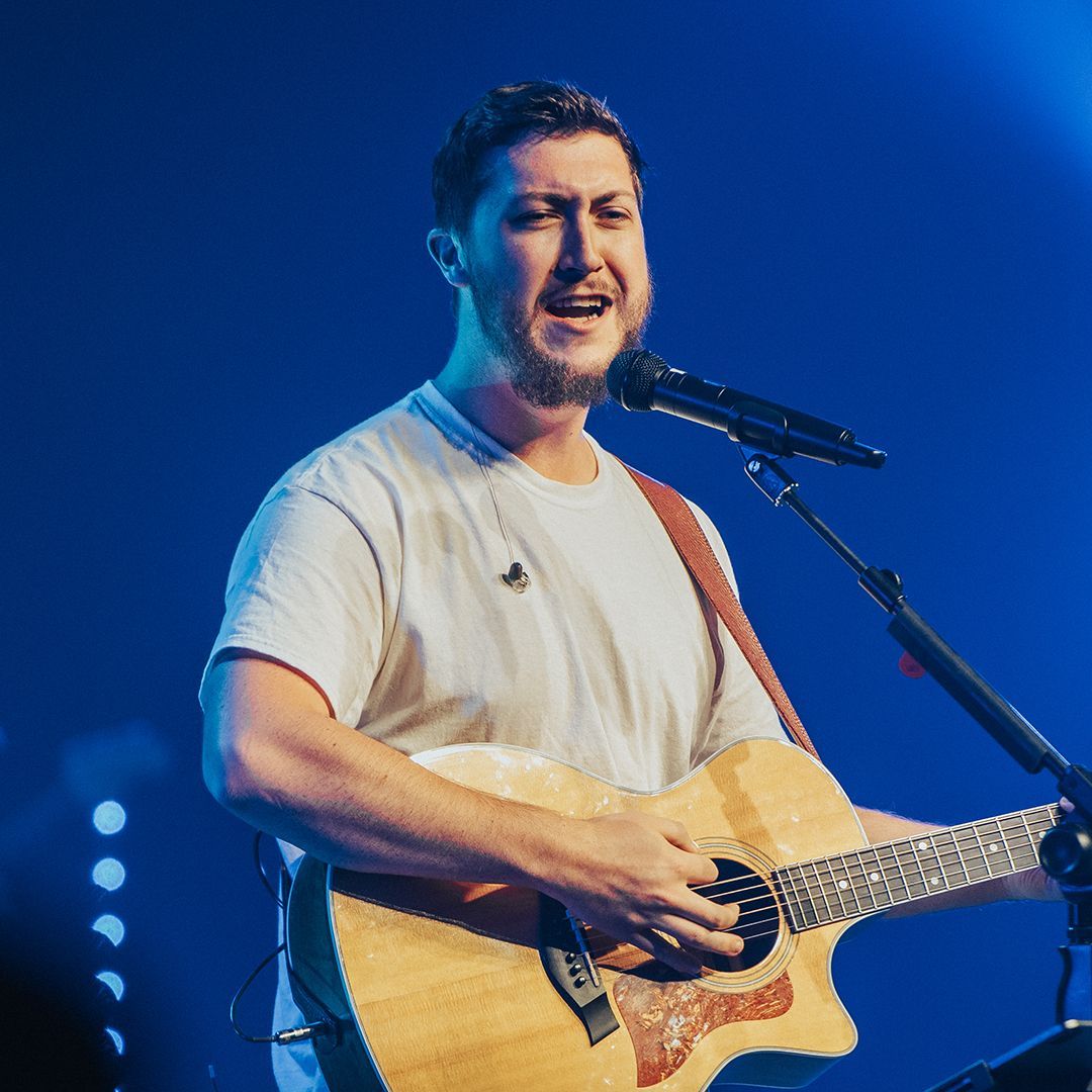 A man singing into a microphone while holding a guitar