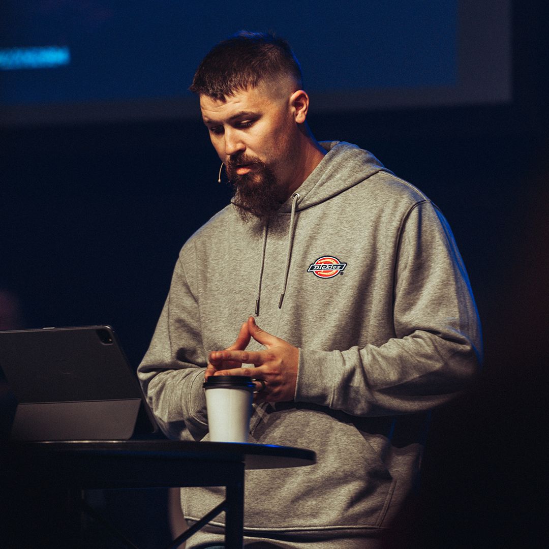 A man with a beard is Teaching at a round table ona stage