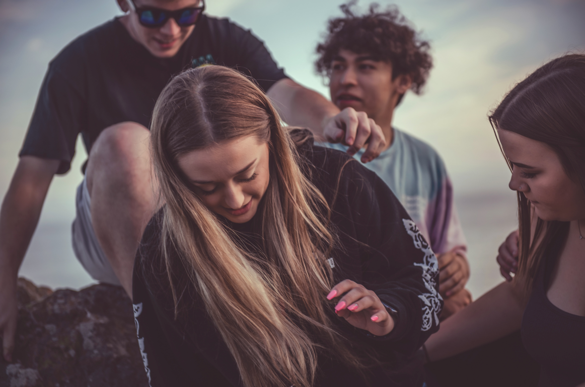 A group of young people are sitting on a rock.