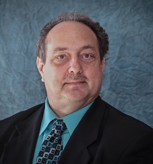 A man in a suit and tie looks at the camera