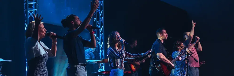 A group of people are singing and playing instruments on a stage.