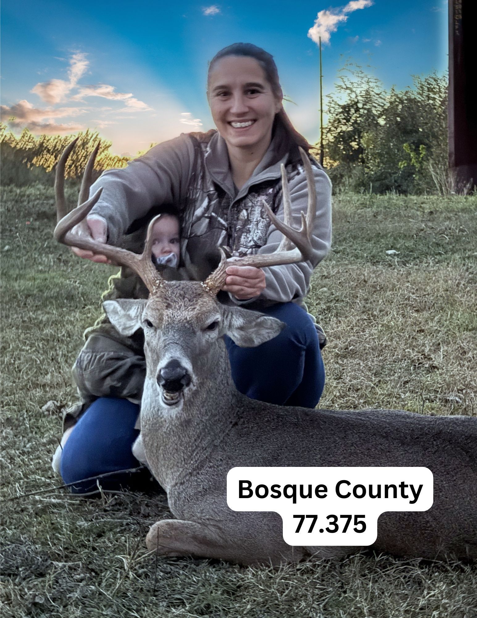 A woman is kneeling down next to a deer in a field.