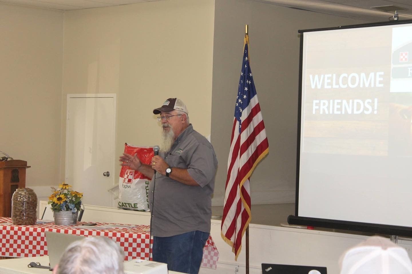 A man stands in front of a screen that says welcome friends