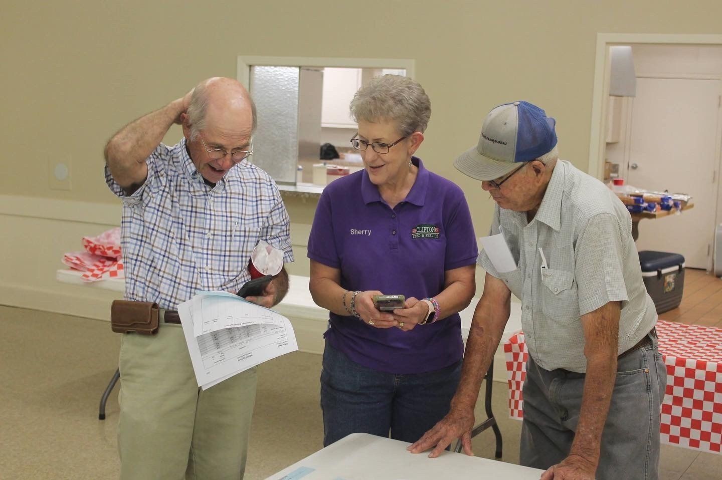 A group of people are standing around a table looking at something.