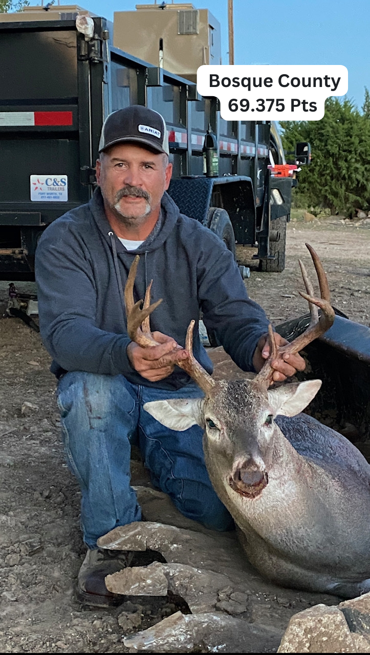 Man kneels with a deer he hunted in Bosque County, Texas. He holds the antlers, and a score of 69.375 Pts is displayed.