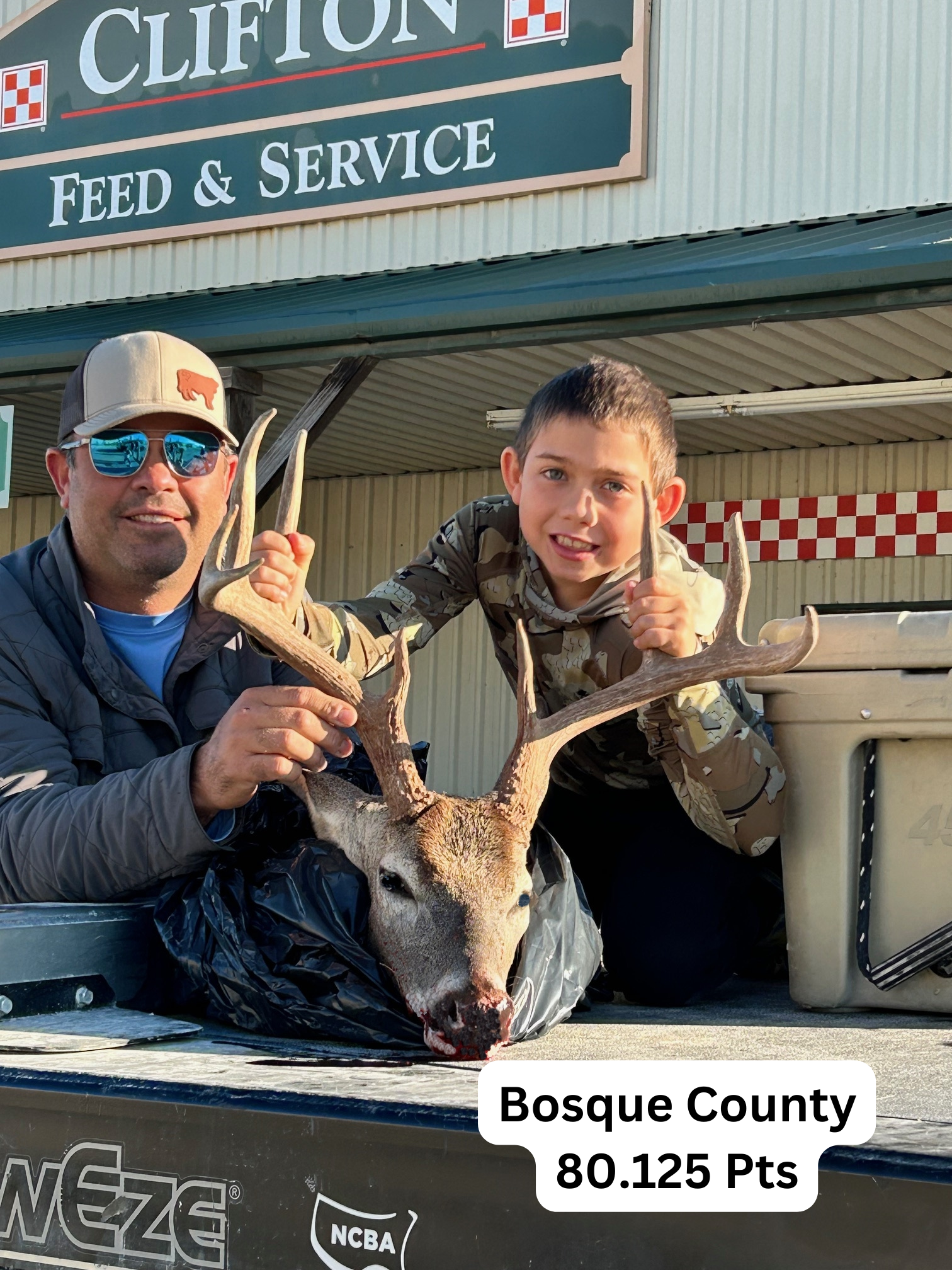 A man and a boy are holding a deer in front of a store.