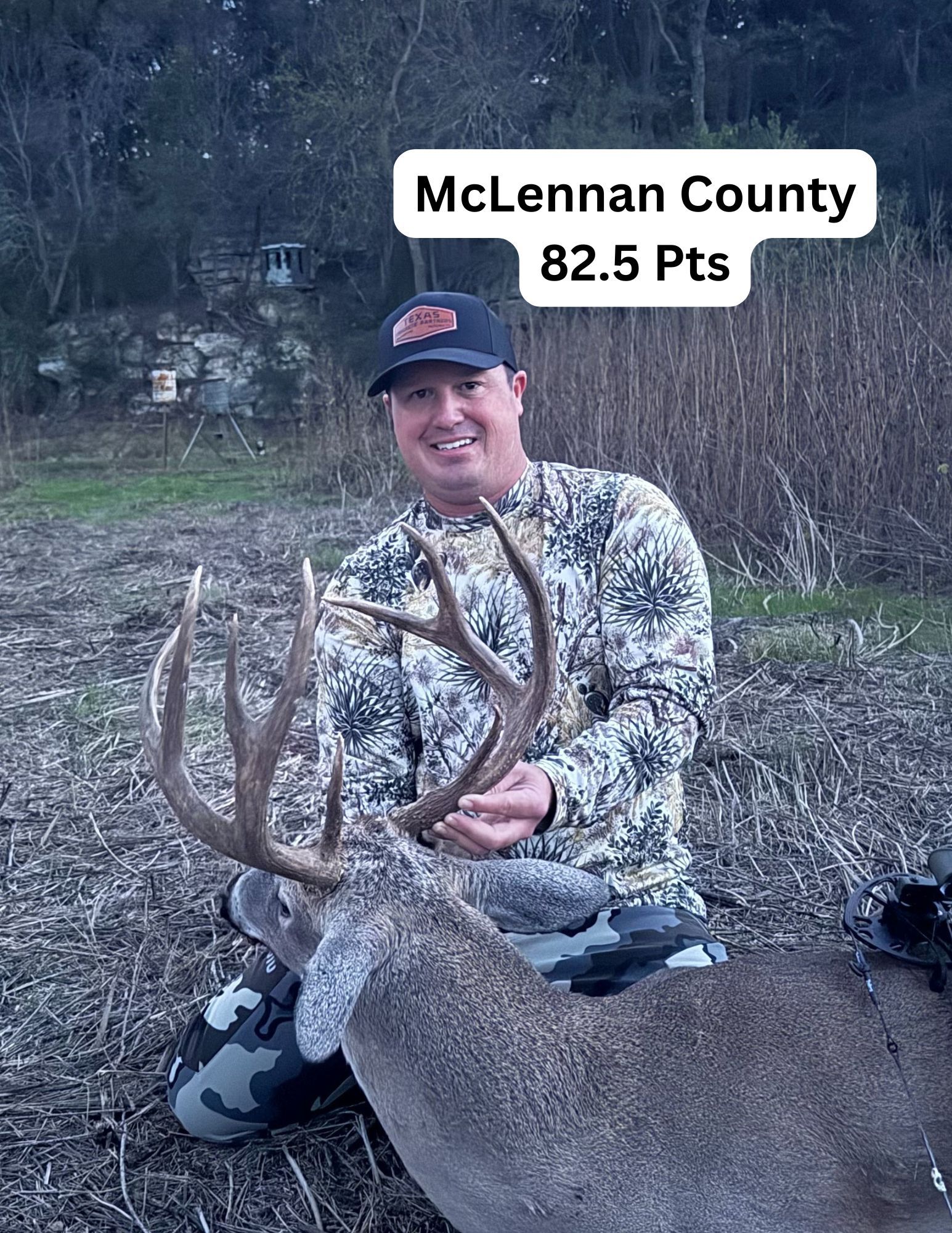 A man is kneeling down next to a large deer in a field.