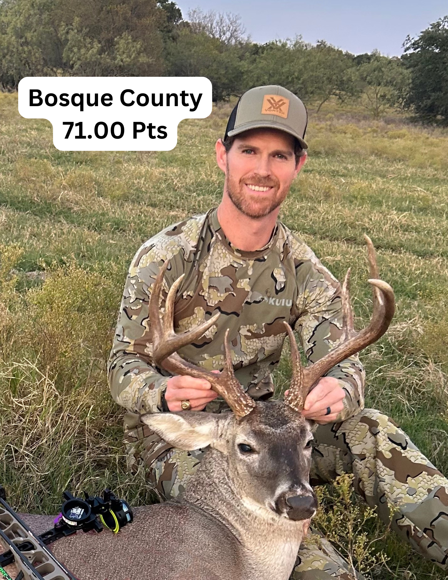 A man in a camouflage uniform is holding a deer in a field.