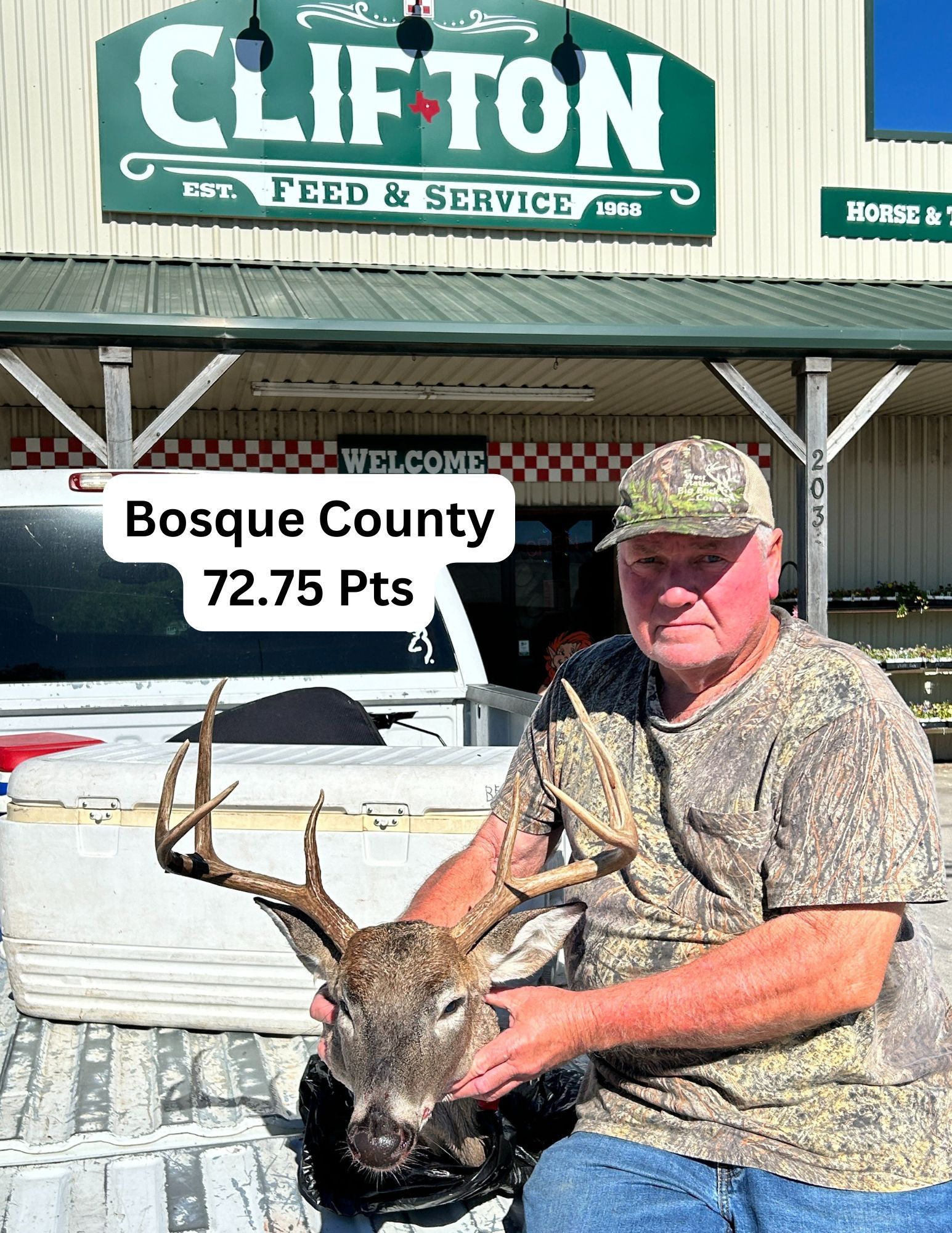 A man is holding a deer in front of a store.