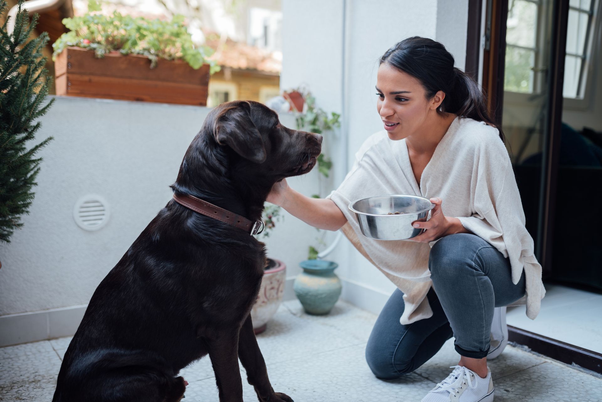 Pet owner holding a bowl of food ready to feed her dog.
