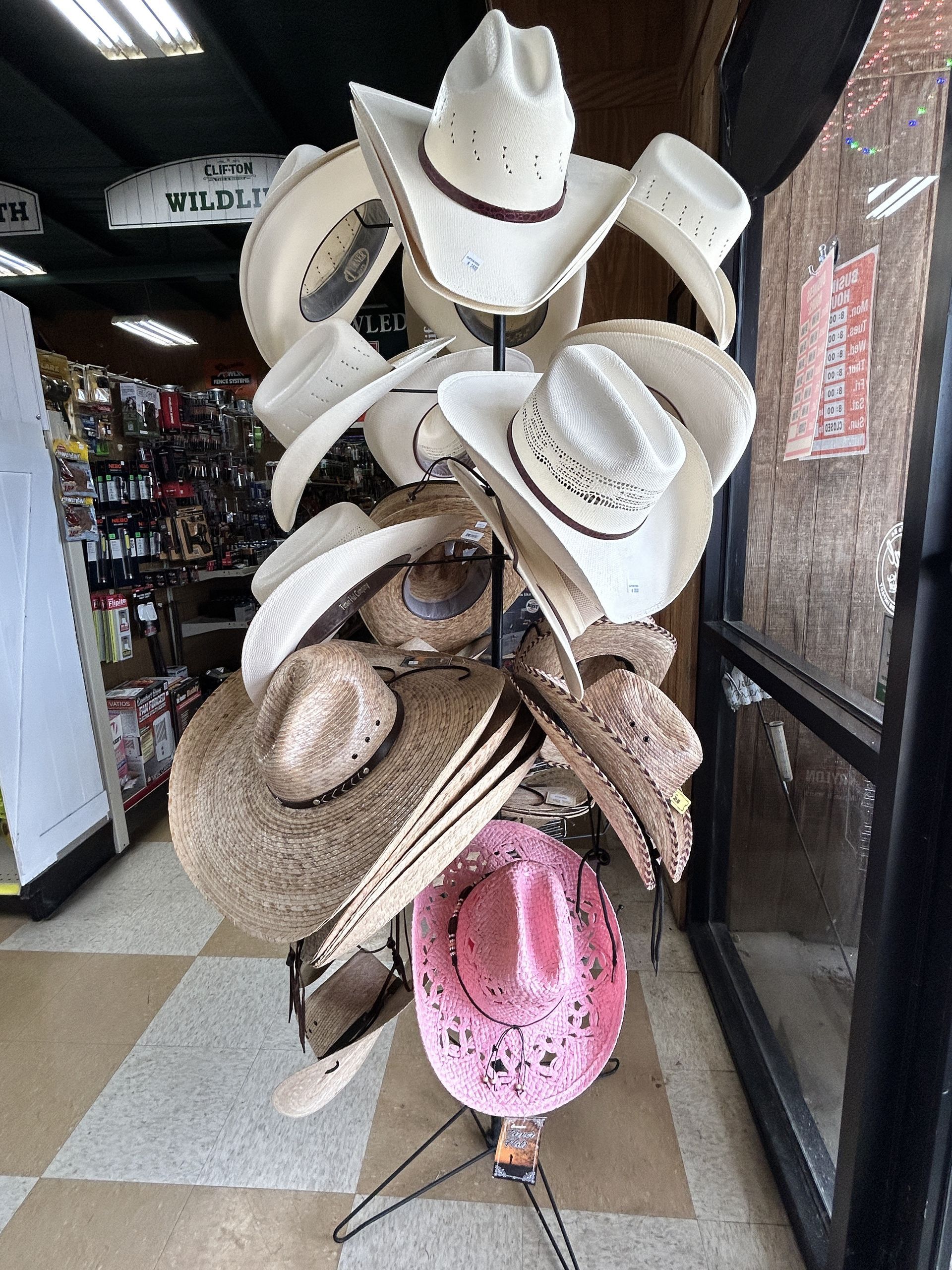 A bunch of cowboy hats are stacked on top of each other on a rack in a store.