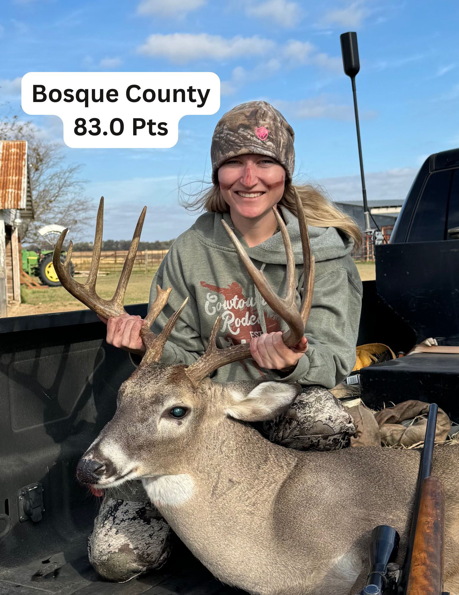 A woman is sitting in the back of a truck holding a deer.