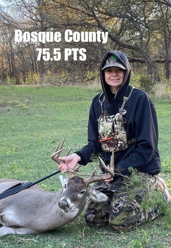 A young person kneels with a deer in Bosque County, Texas. They hold the deer's antlers. Score: 75.5 PTS.