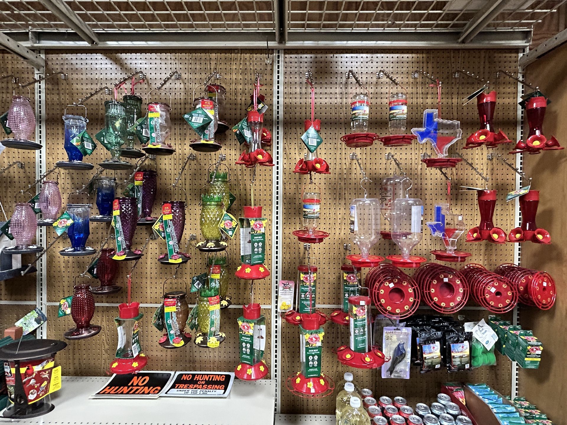 There are many different types of hummingbird feeders hanging on the wall.