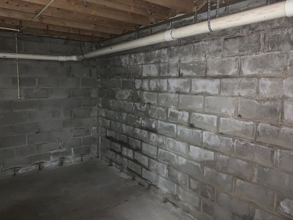 a brick wall in a basement with pipes coming out of it .