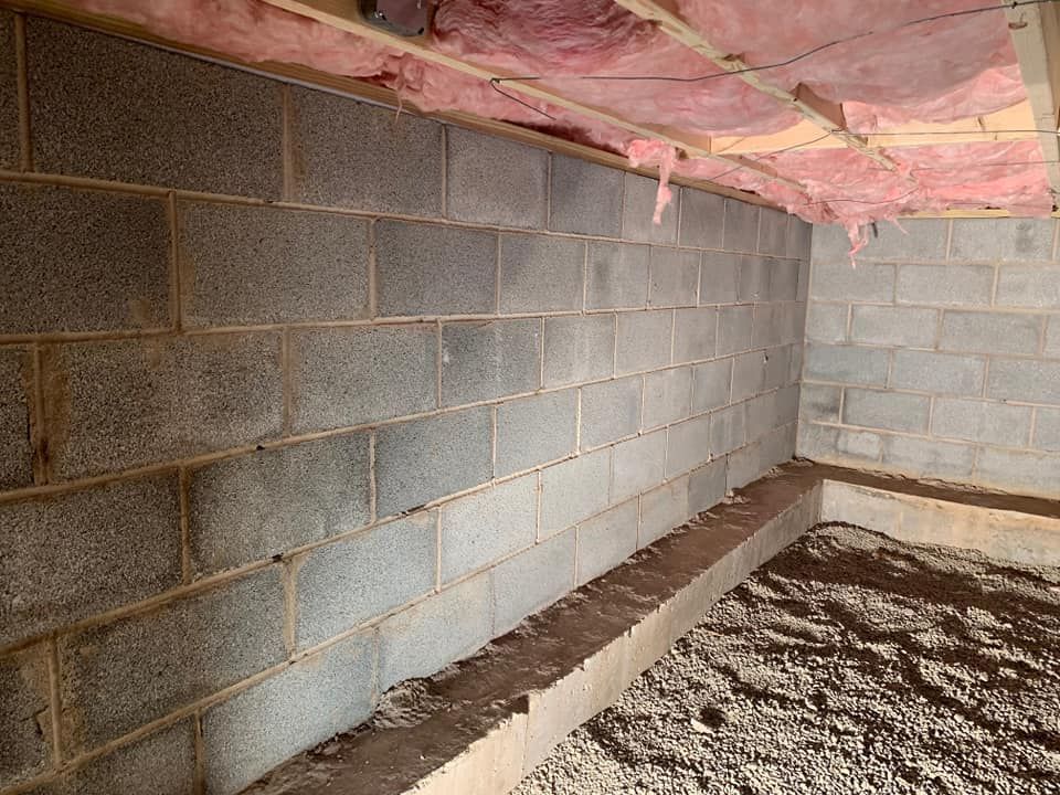 a basement with brick walls and pink insulation on the ceiling .