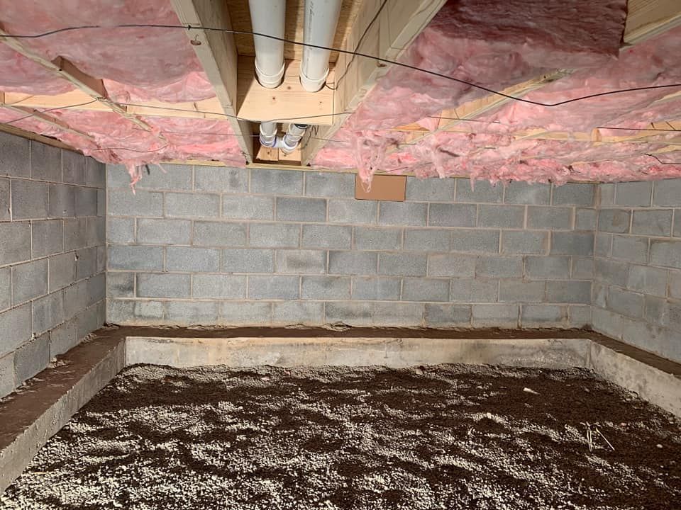 a basement with brick walls and insulation on the ceiling .
