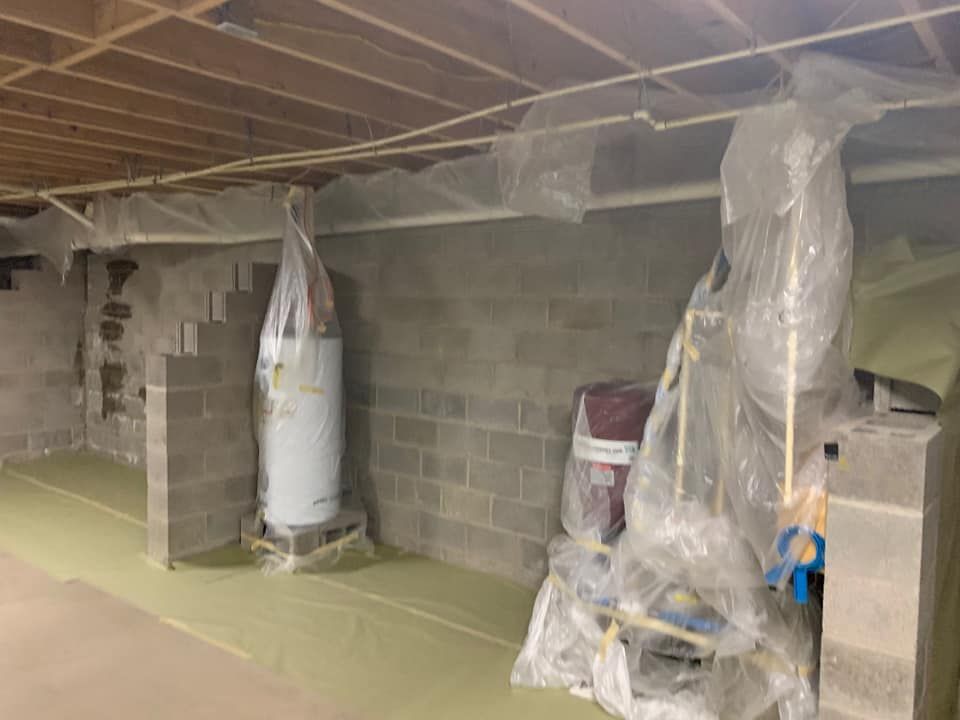 a basement with a water heater and a broom covered in plastic .