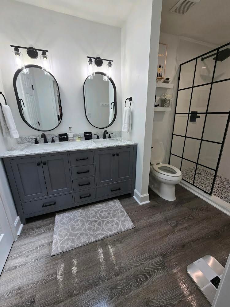 A bathroom with two sinks , a toilet , and a walk in shower.