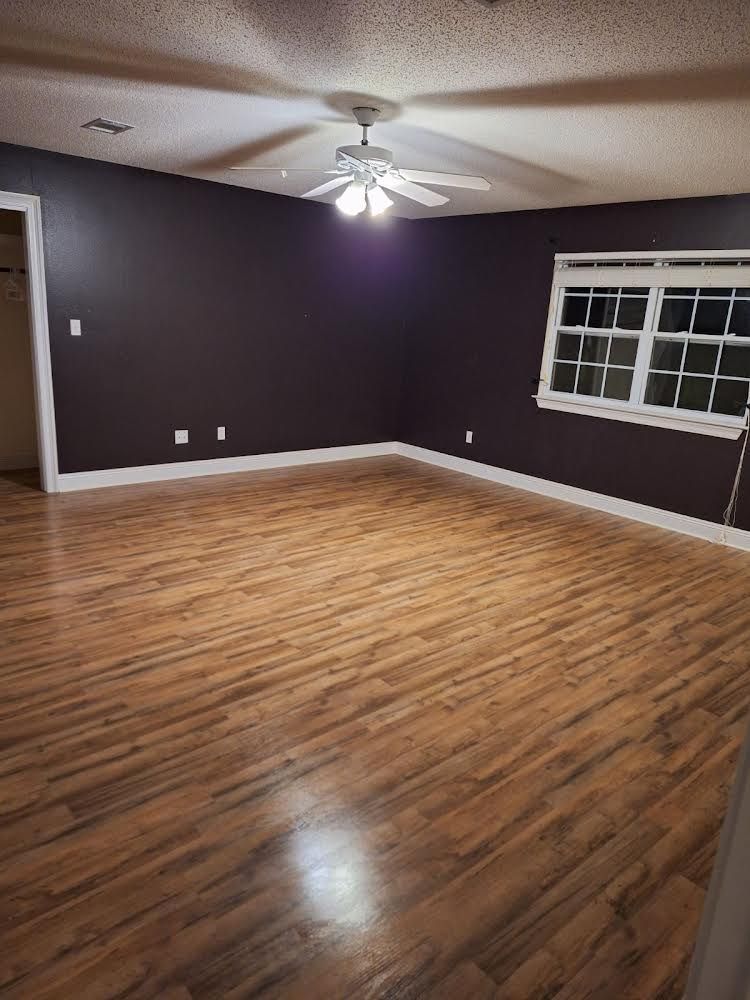 An empty living room with hardwood floors and a ceiling fan.