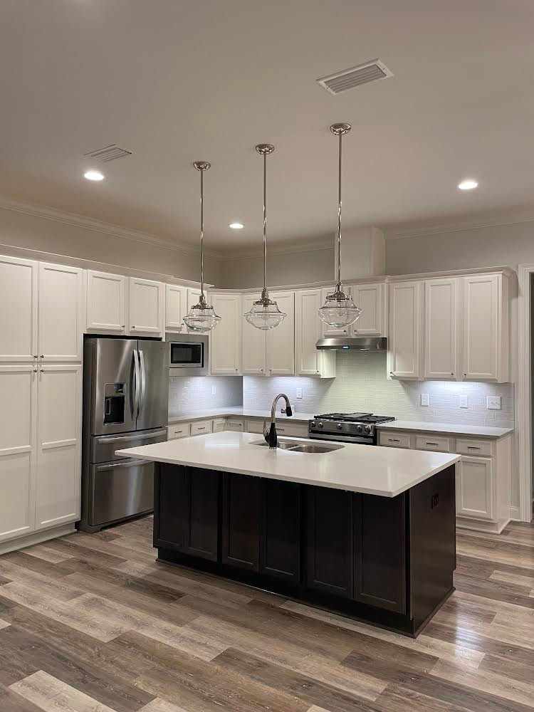 A kitchen with white cabinets , stainless steel appliances , and a large island.