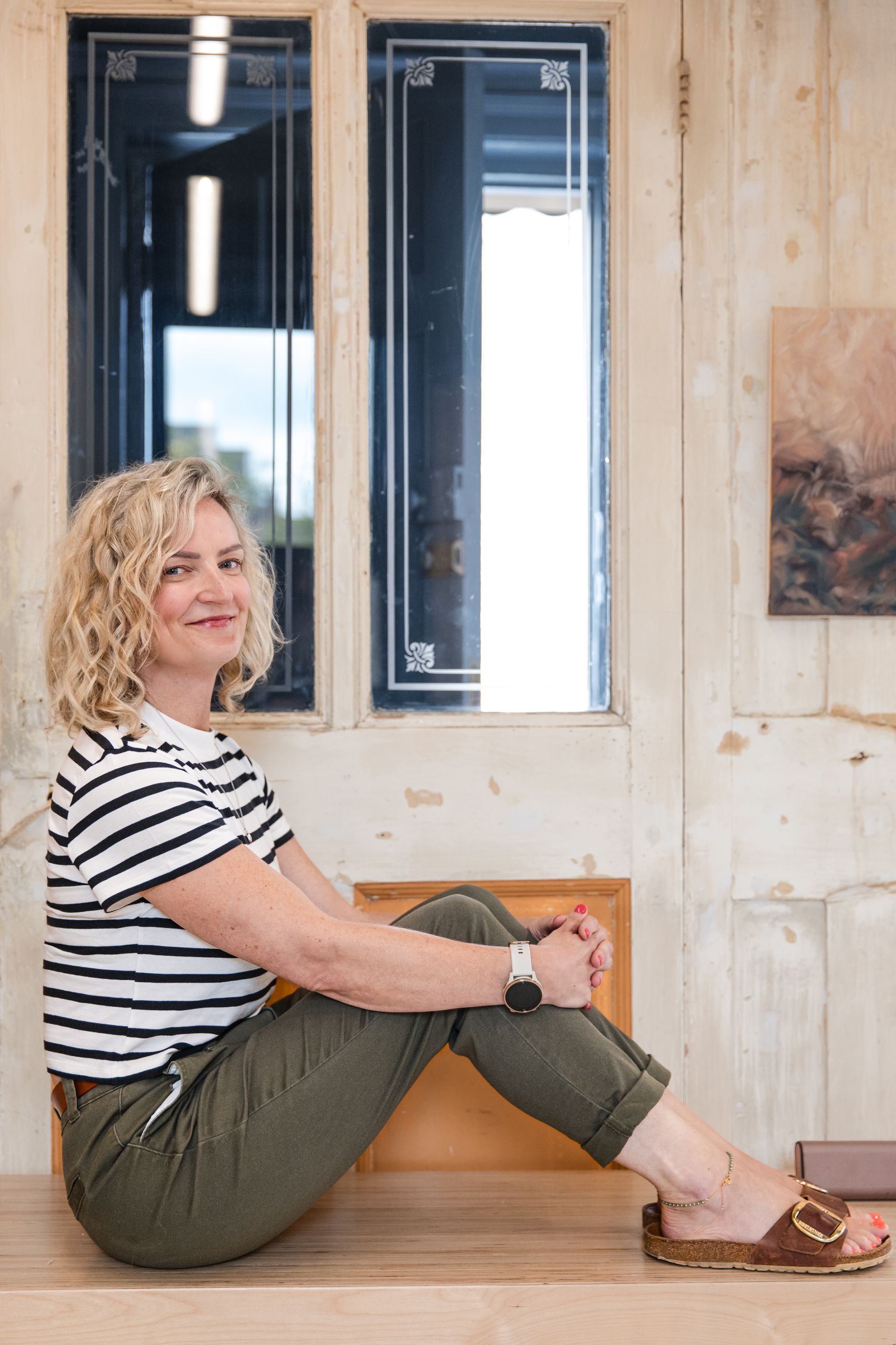 Our MD Nicola Theaker smiling at the camera, in front of a beige wall with mirrors on it