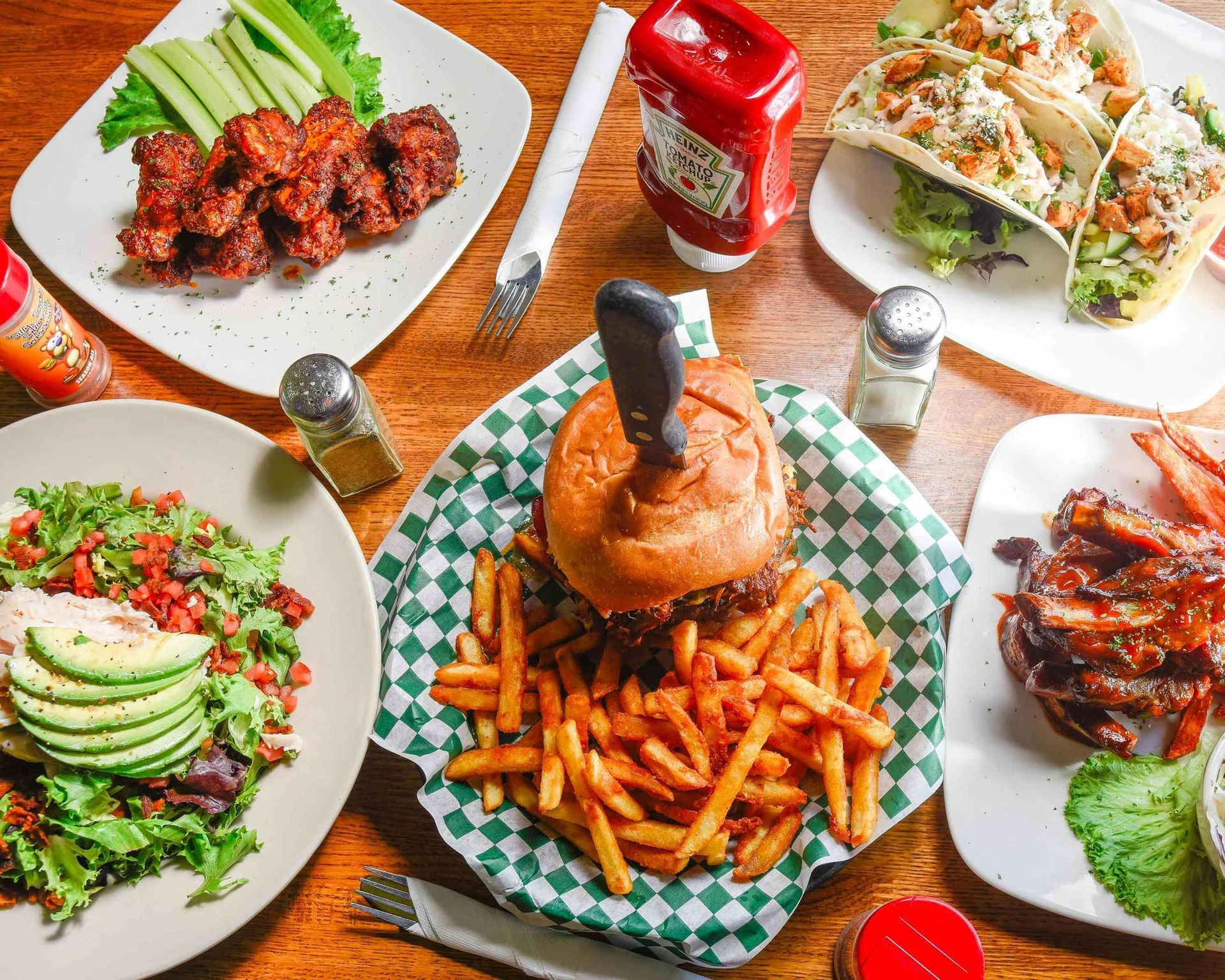 A table topped with plates of food including a hamburger and french fries.