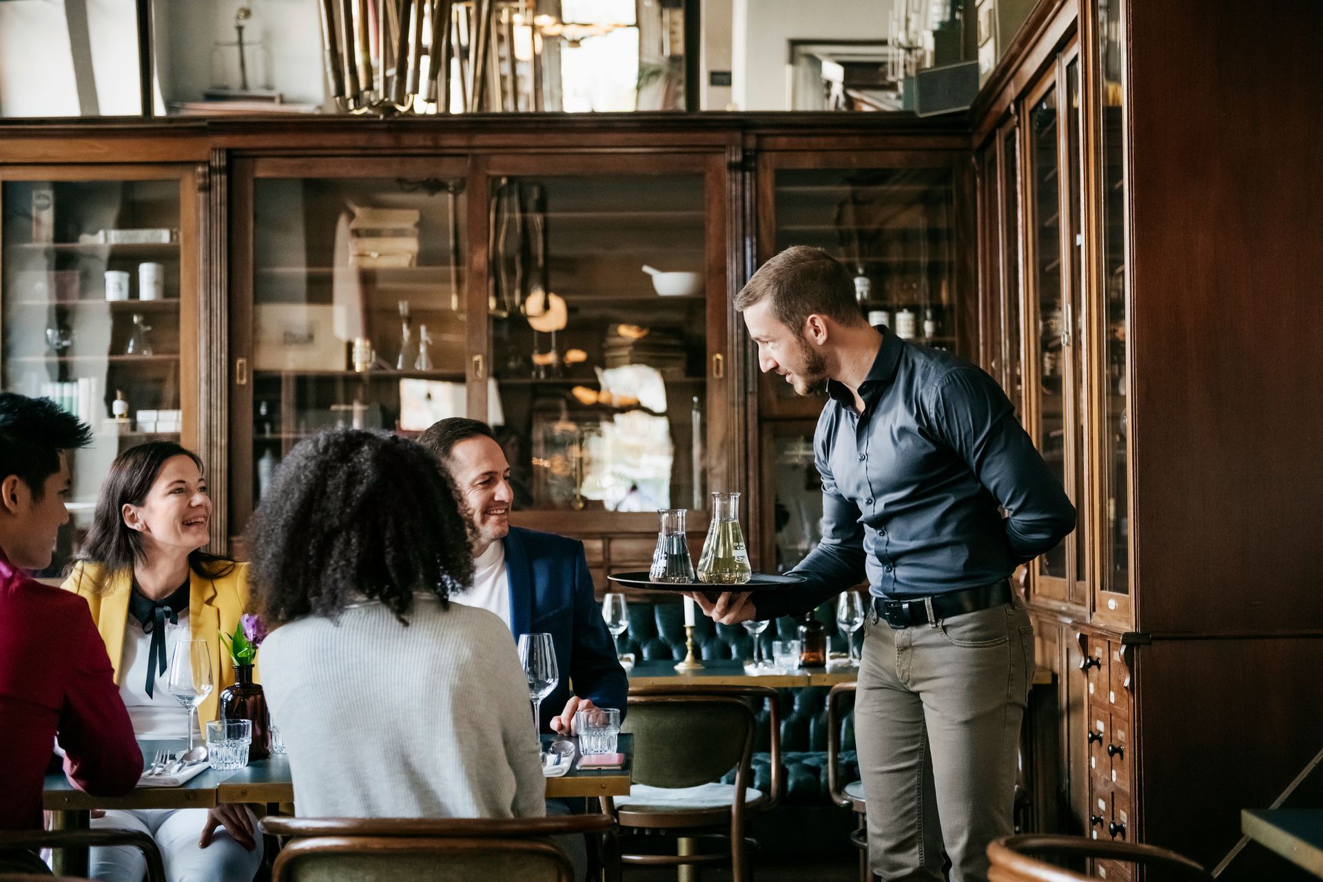 A waiter is serving a group of people in a restaurant.