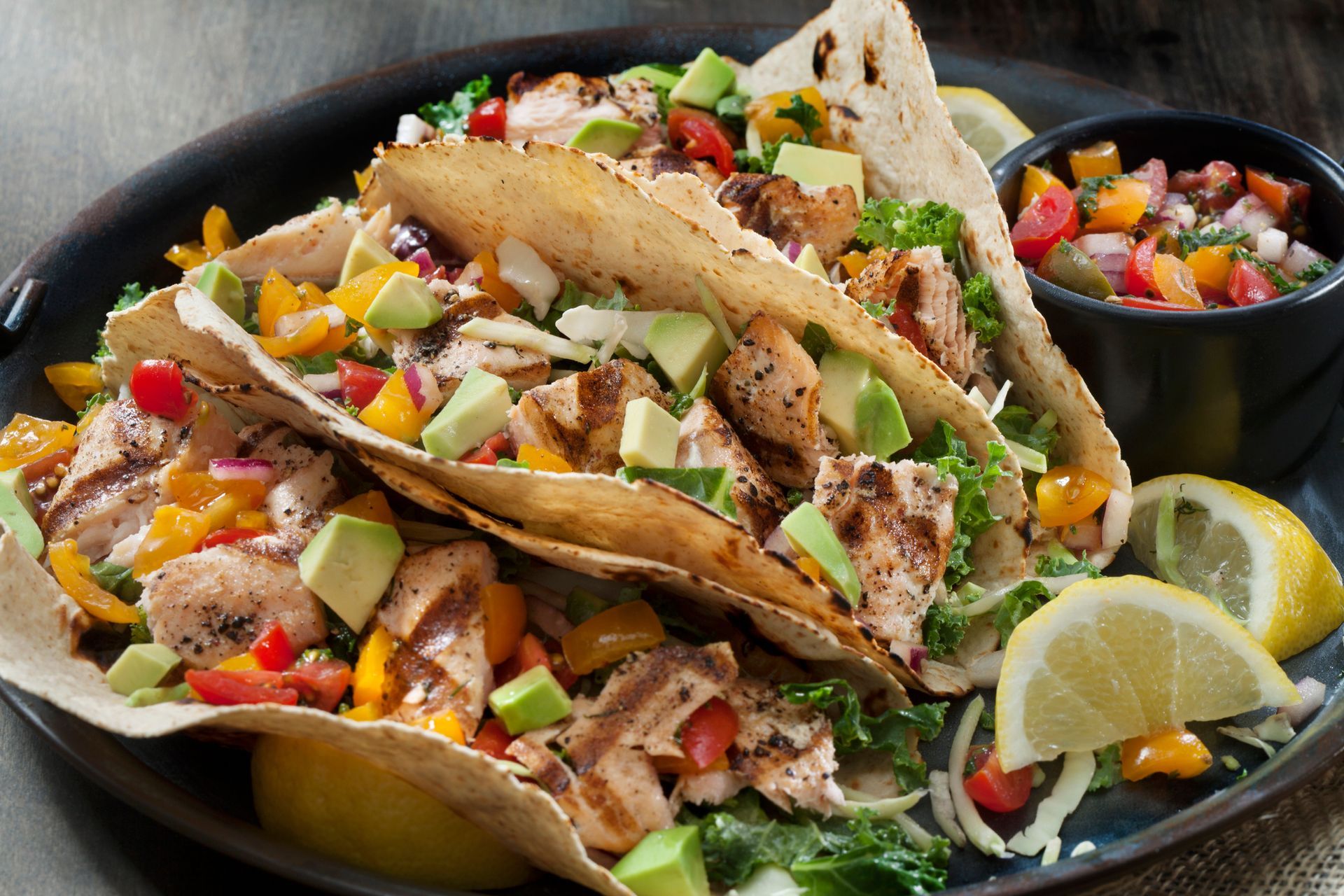 A close up of a plate of food with tacos and salsa on a table.