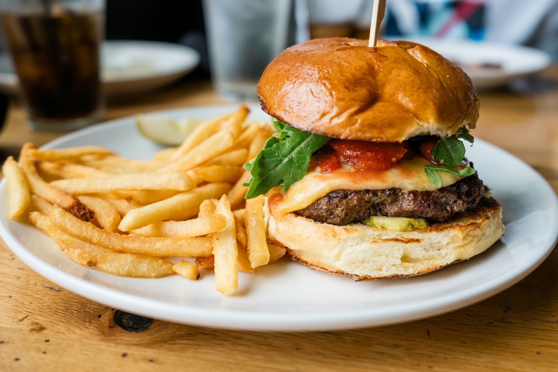 A hamburger and french fries on a white plate on a table.
