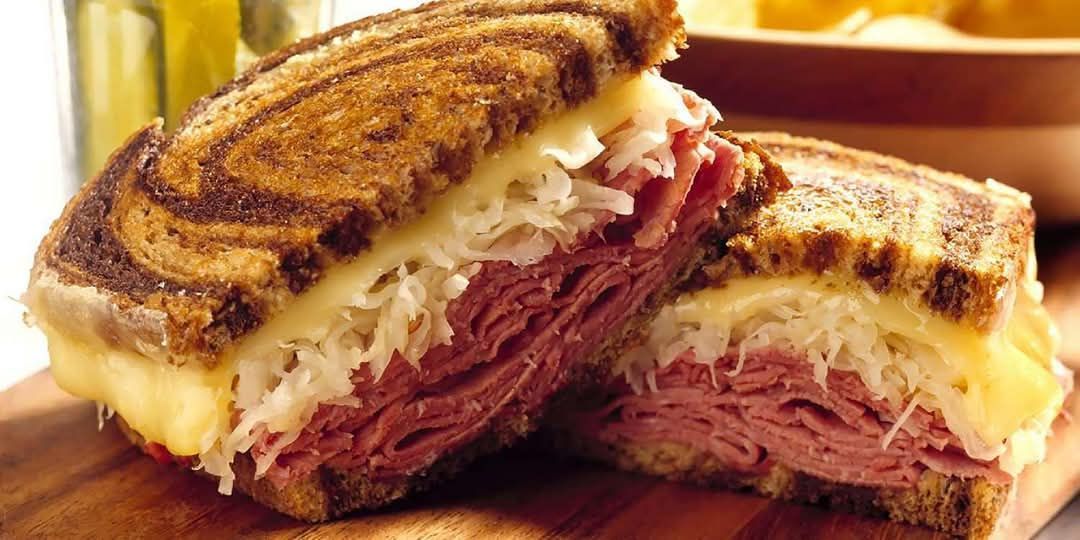 A grilled cheese sandwich is stacked on top of each other on a wooden cutting board.