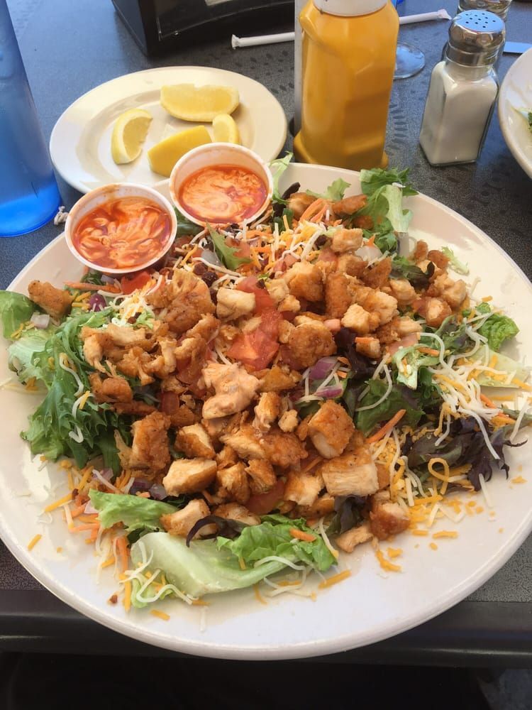 A salad in a white bowl on a white wooden table.