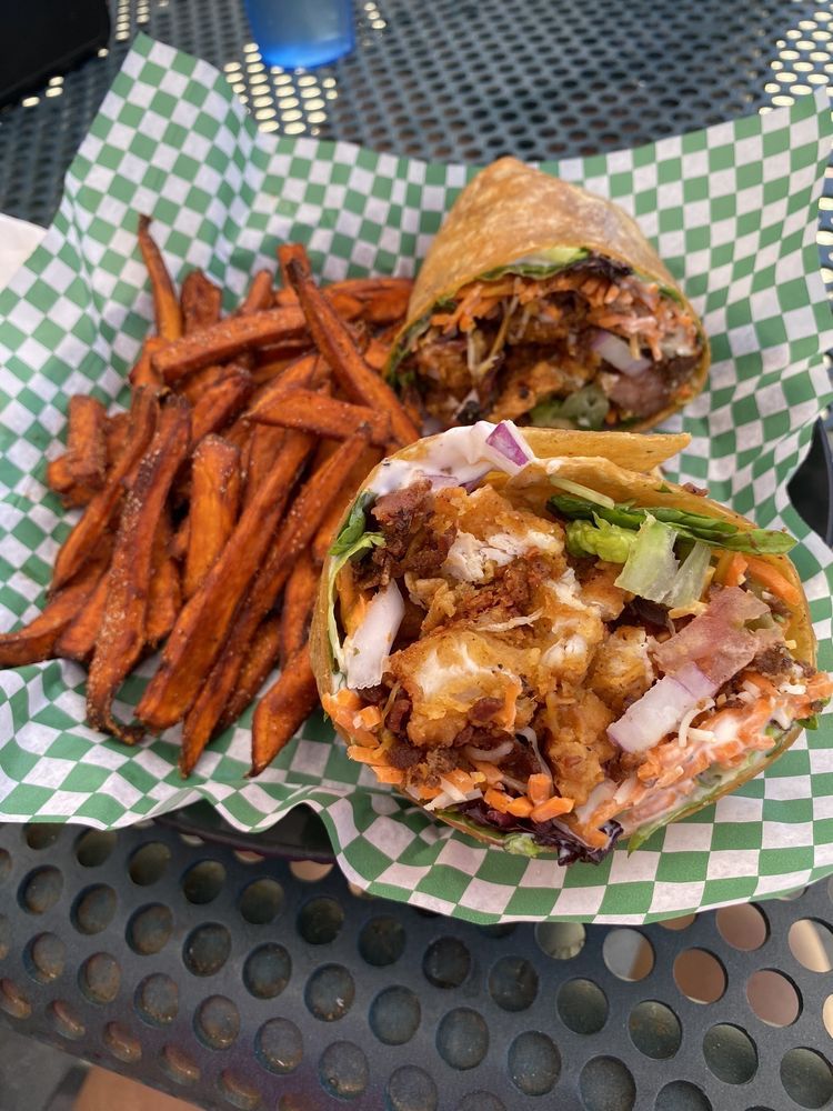 A chicken wrap is cut in half and stacked on top of each other on a wooden table.