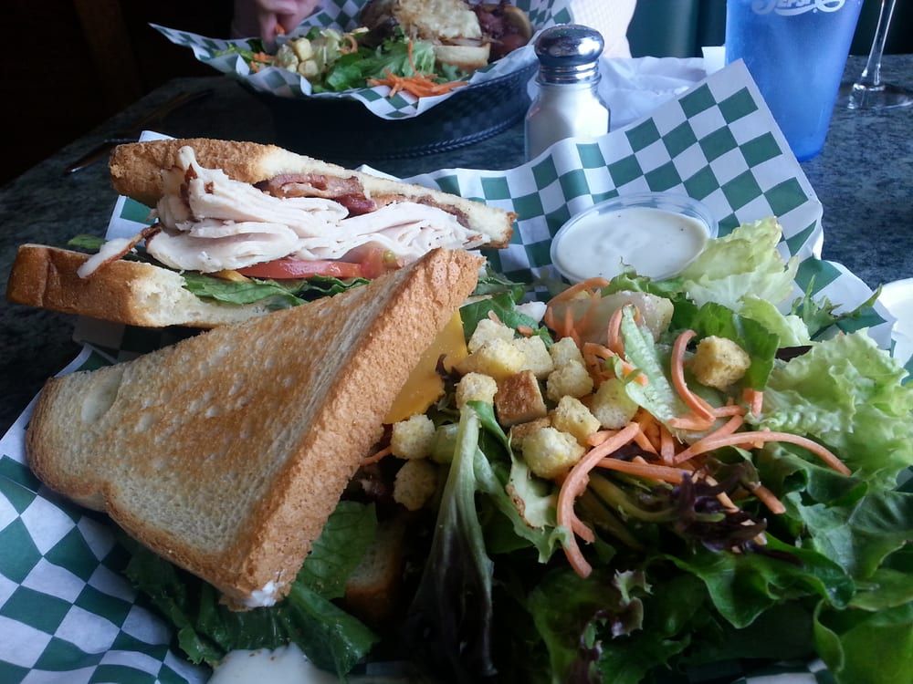 A close up of a sandwich on a wooden cutting board.