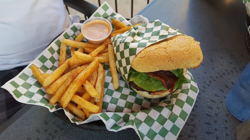 A double cheeseburger is sitting on a wooden cutting board.