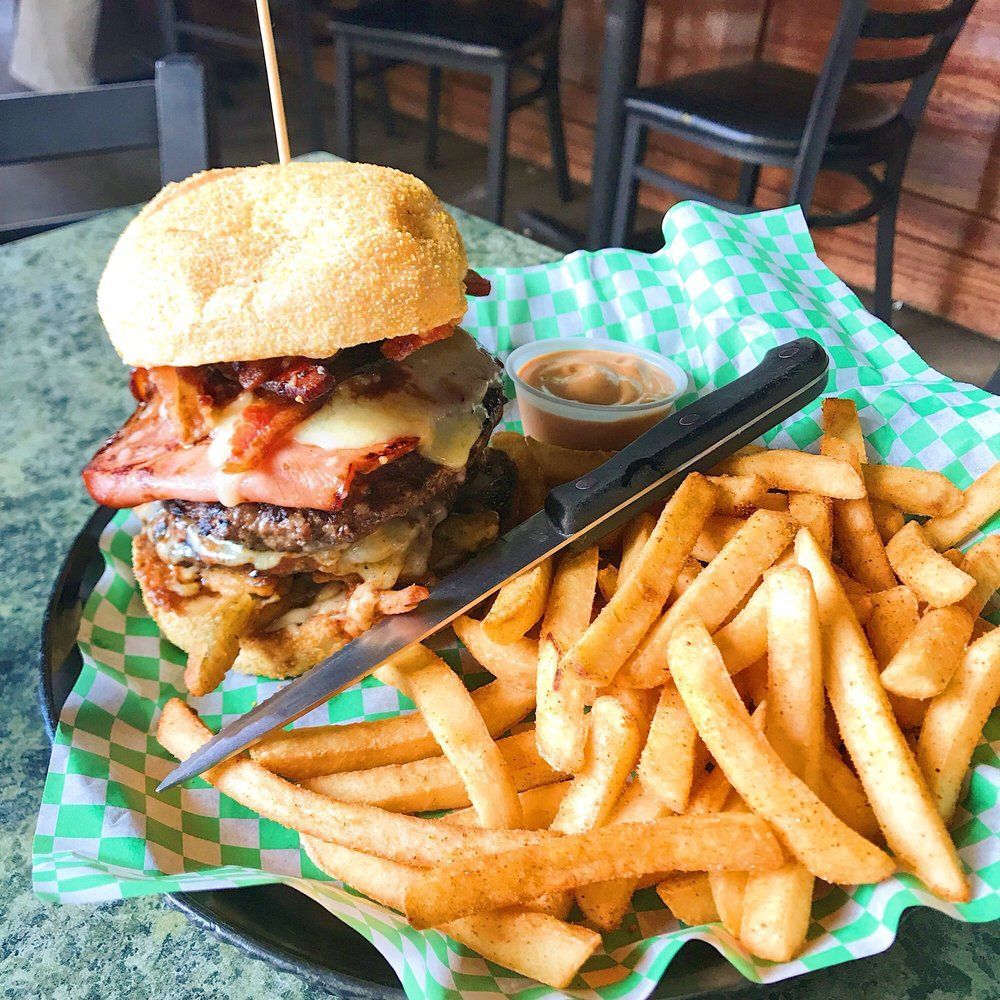 A hamburger and french fries are on a wooden cutting board.
