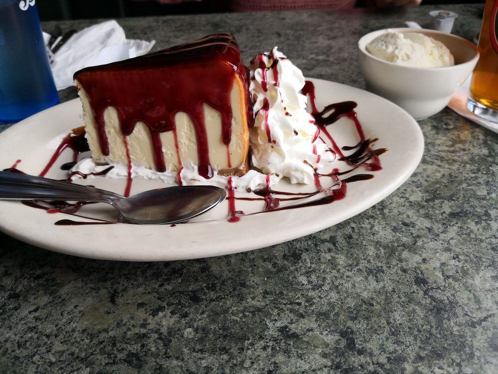 A strawberry milkshake with whipped cream and chocolate sauce in a glass with a straw.