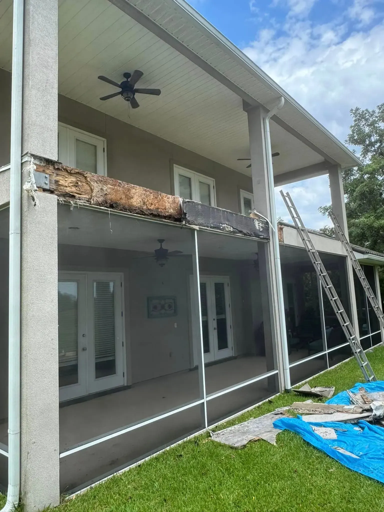 A large house with a screened in porch and a ceiling fan.