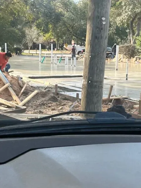 A man is working on a concrete driveway in a parking lot.