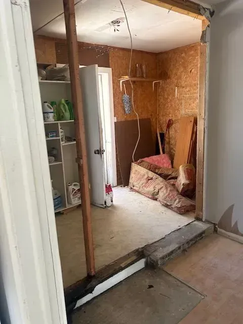 A room with a door open and a mattress on the floor.