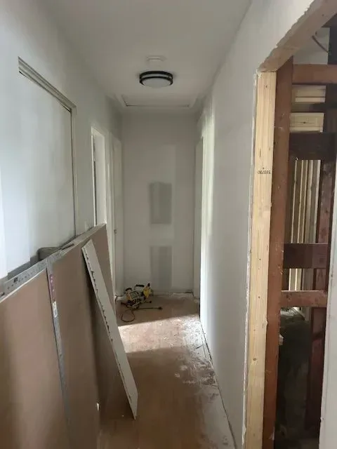 A hallway in a house under construction with a light on the ceiling.