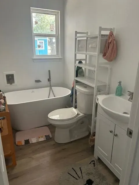 A bathroom with a tub , toilet , sink and window.