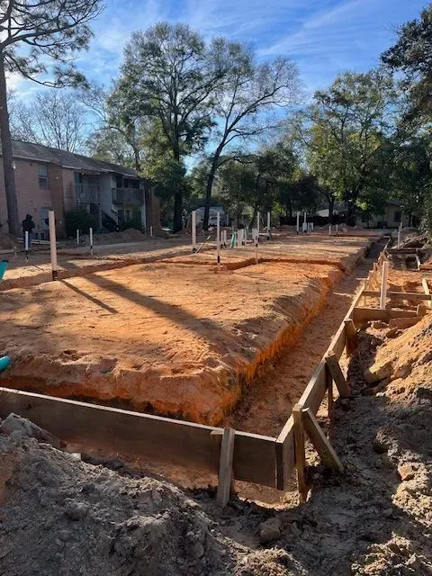 A construction site with a lot of dirt and trees in the background.