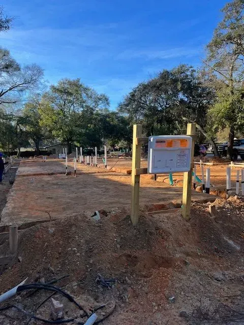 A wooden post with a sign on it is in the middle of a dirt field.
