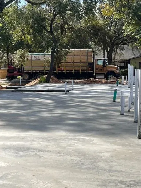 A truck is driving down a concrete driveway next to trees.