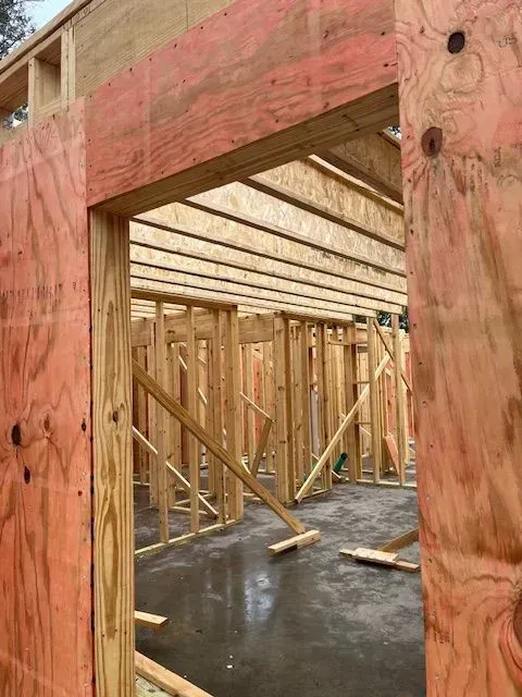 A house is being built with wooden beams and a concrete floor.