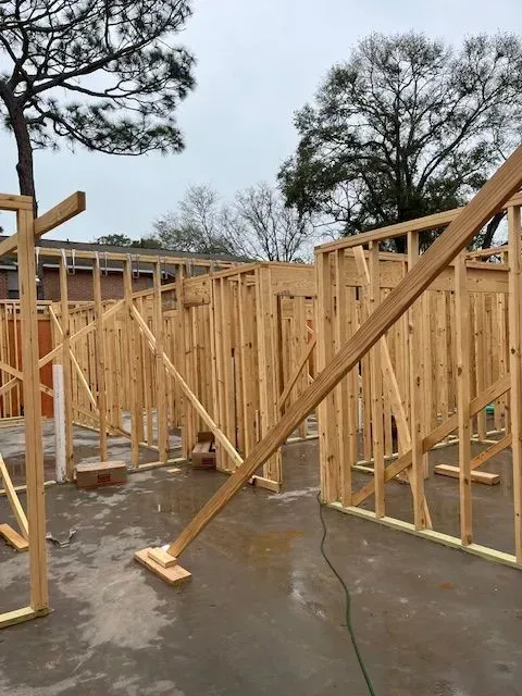 A house is being built with wooden frames and a tree in the background