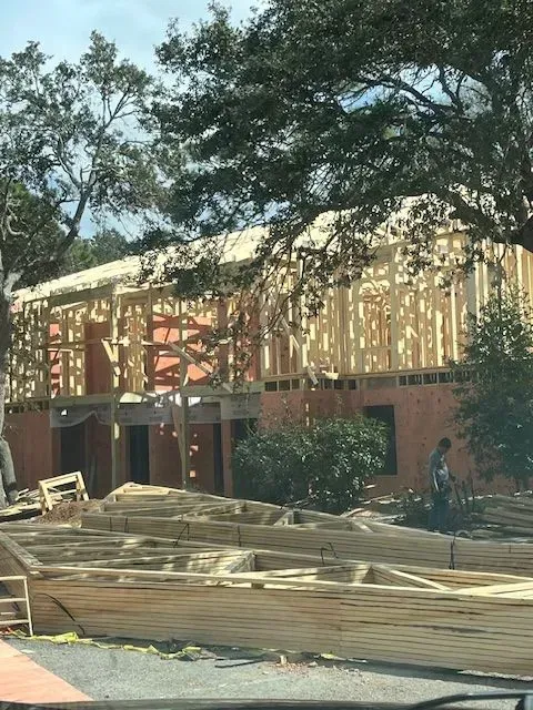 A house is being built with a lot of wood in front of it.