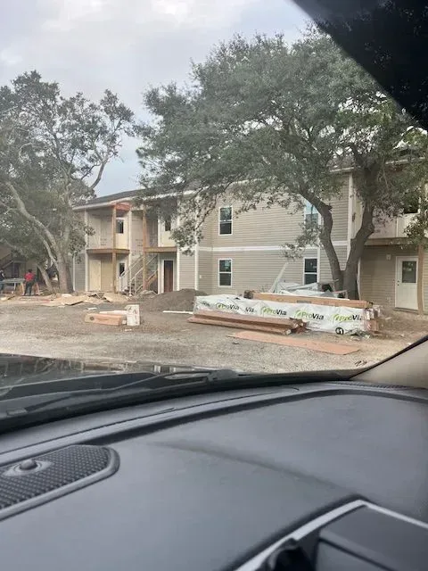 A car is parked in front of a building under construction.