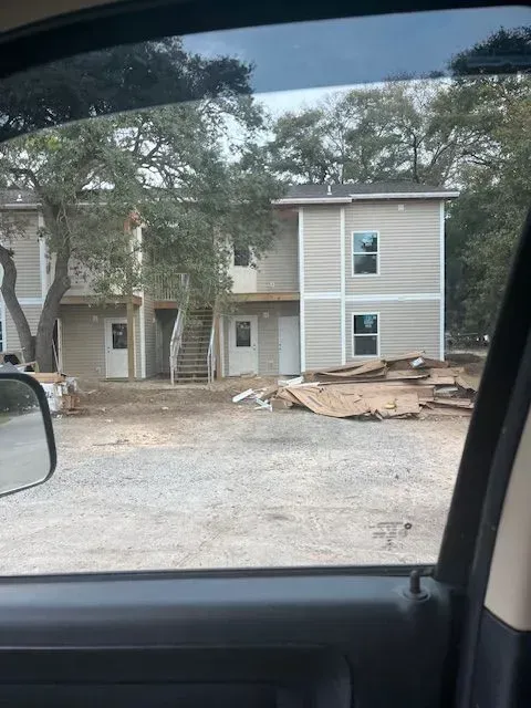 A car is parked in front of a building under construction.